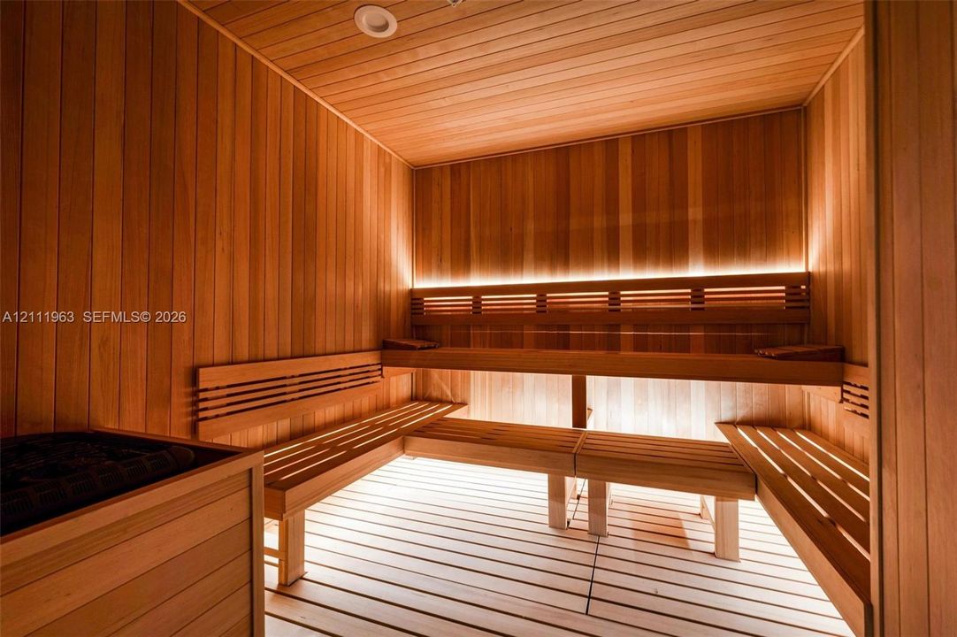 Sauna featuring full wood-panel cladding, multi-level slatted wood bench seating, integrated LED accent lighting, and a built-in heating unit