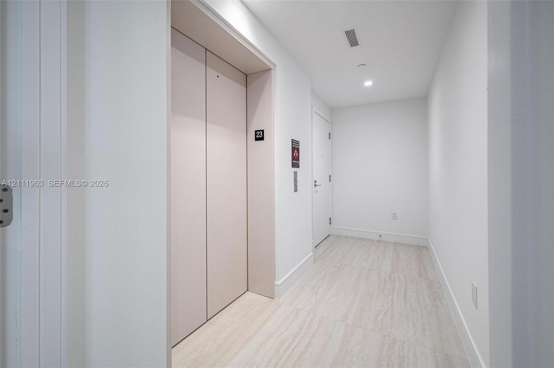 Private elevator access featuring matte-finish double doors and large-format stone-tile flooring