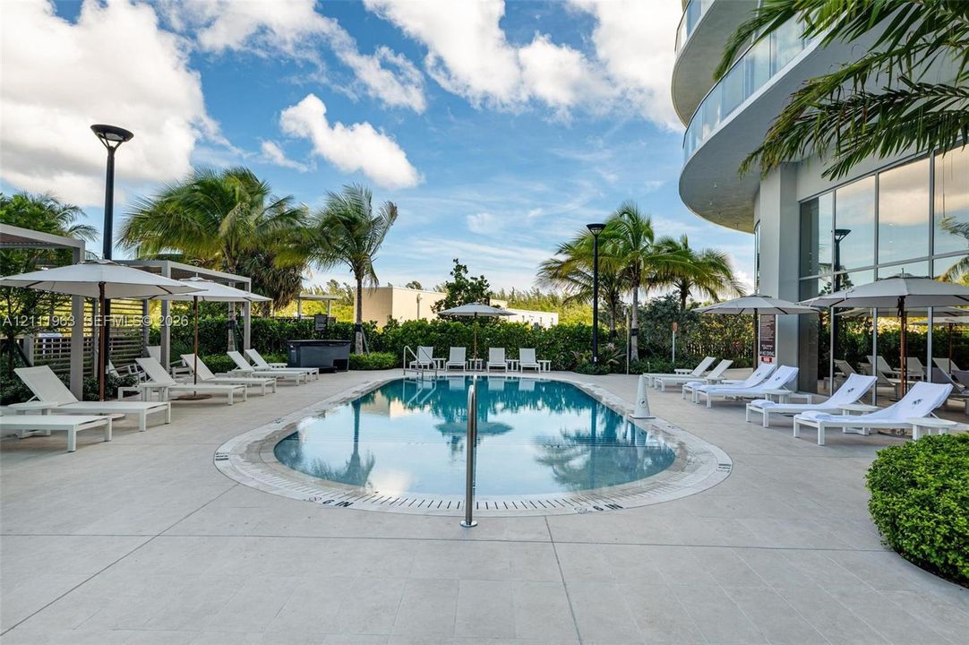 Swimming pool featuring a concrete deck, built-in structural poles, and perimeter landscaping