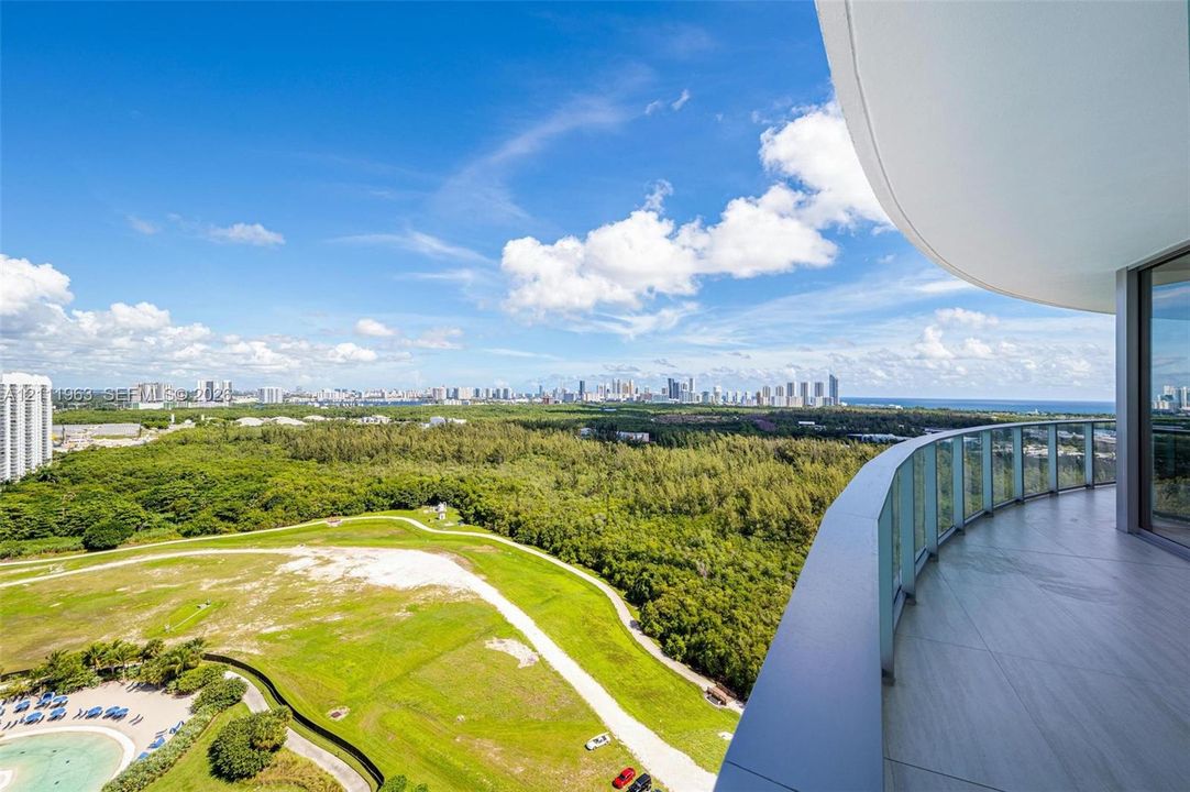 Curved balcony featuring large-format porcelain tile flooring and a glass panel railing