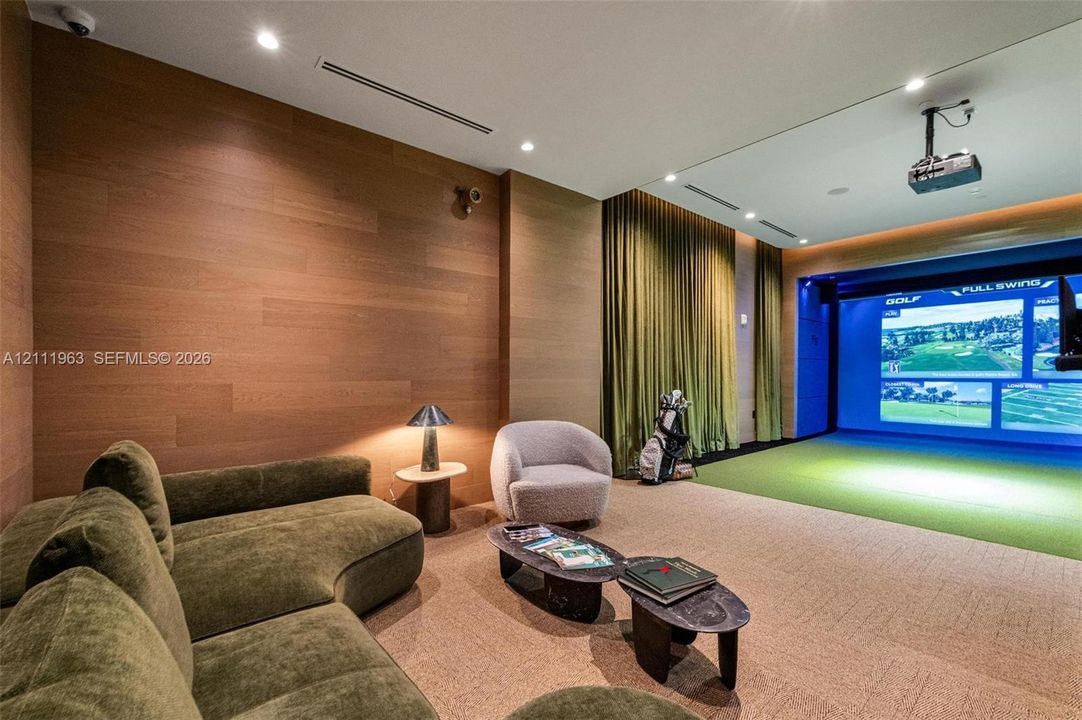 Media room featuring wood-paneled walls, recessed ceiling lighting, a built-in projection system, and a designated synthetic turf simulation area