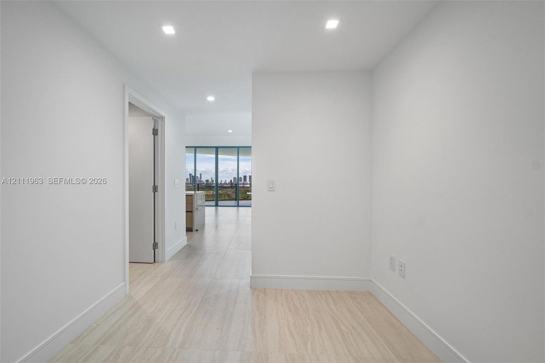 Interior space featuring neutral white walls, recessed ceiling lighting, and large-format tile flooring