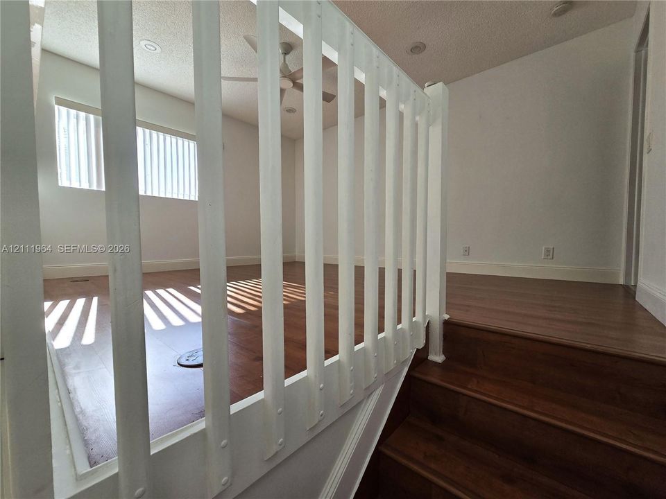 Wood-finish flooring, white vertical baluster railing, recessed ceiling lighting, and a ceiling fan