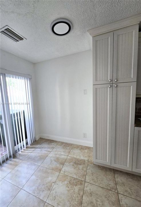 Tall white beadboard-style cabinetry, square stone-finish floor tiling, and a recessed ceiling light fixture
