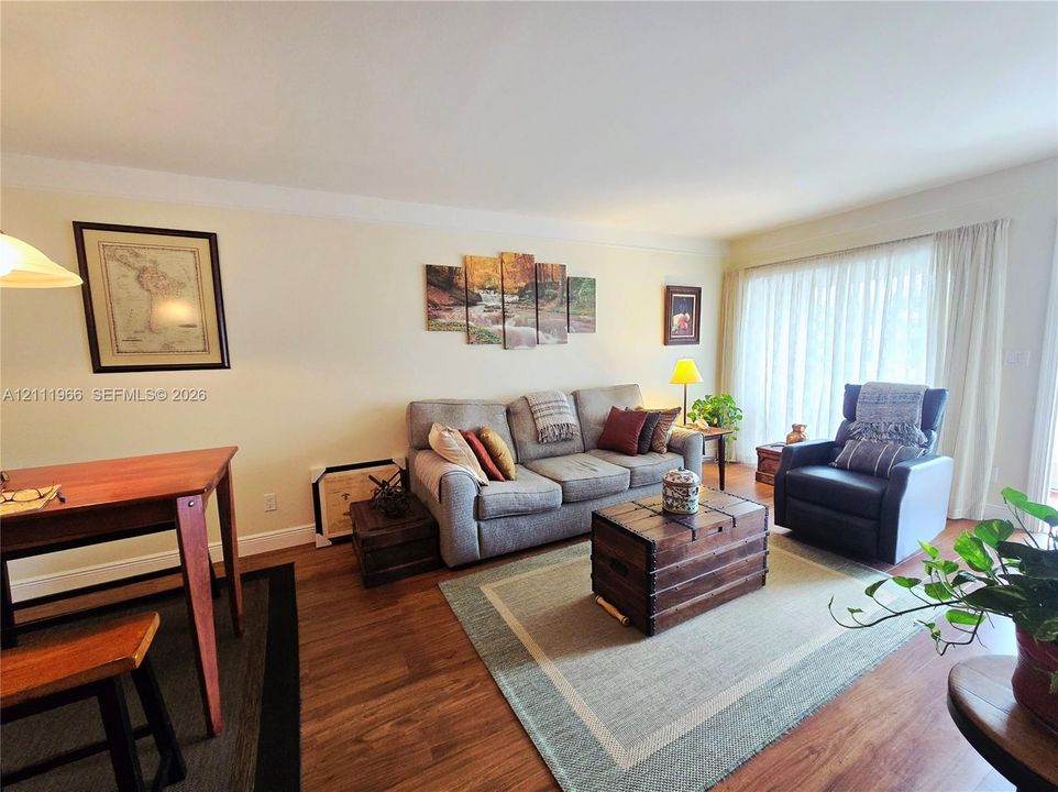 Living area featuring wood-finish flooring and floor-to-ceiling window drapery