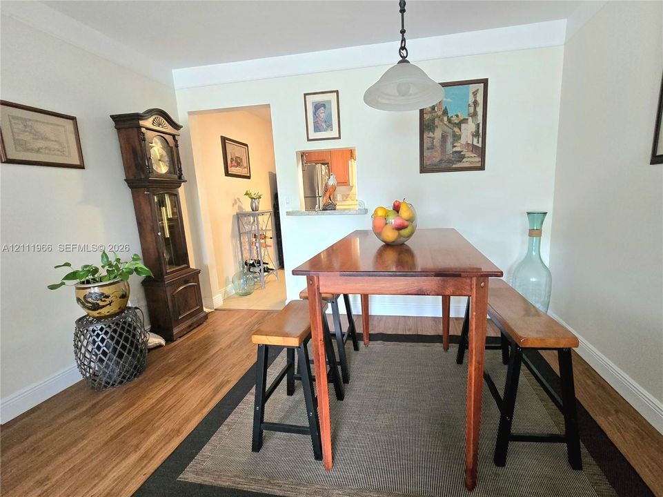 Wood-finish flooring, neutral wall tones, pendant lighting fixture, and a pass-through wall cutout