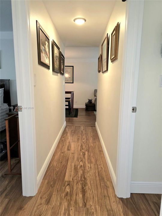Hallway featuring wood-finish flooring and a flush-mount ceiling light fixture