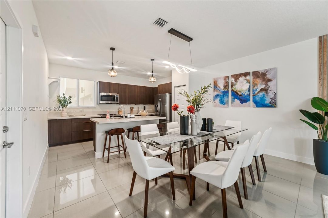 Kitchen featuring dark wood-finish cabinetry, solid-surface countertops, recessed lighting, pendant light fixtures, and large-format tile flooring
