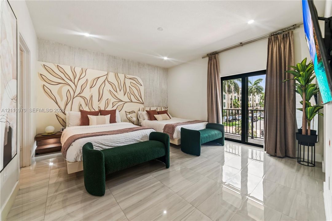 Large bedroom featuring polished tile flooring, a custom decorative wall mural, recessed lighting, and sliding glass doors with direct exterior balcony access