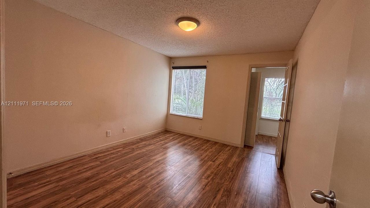 Interior room featuring wood-finish flooring, a flush-mount light fixture, and a single-pane window