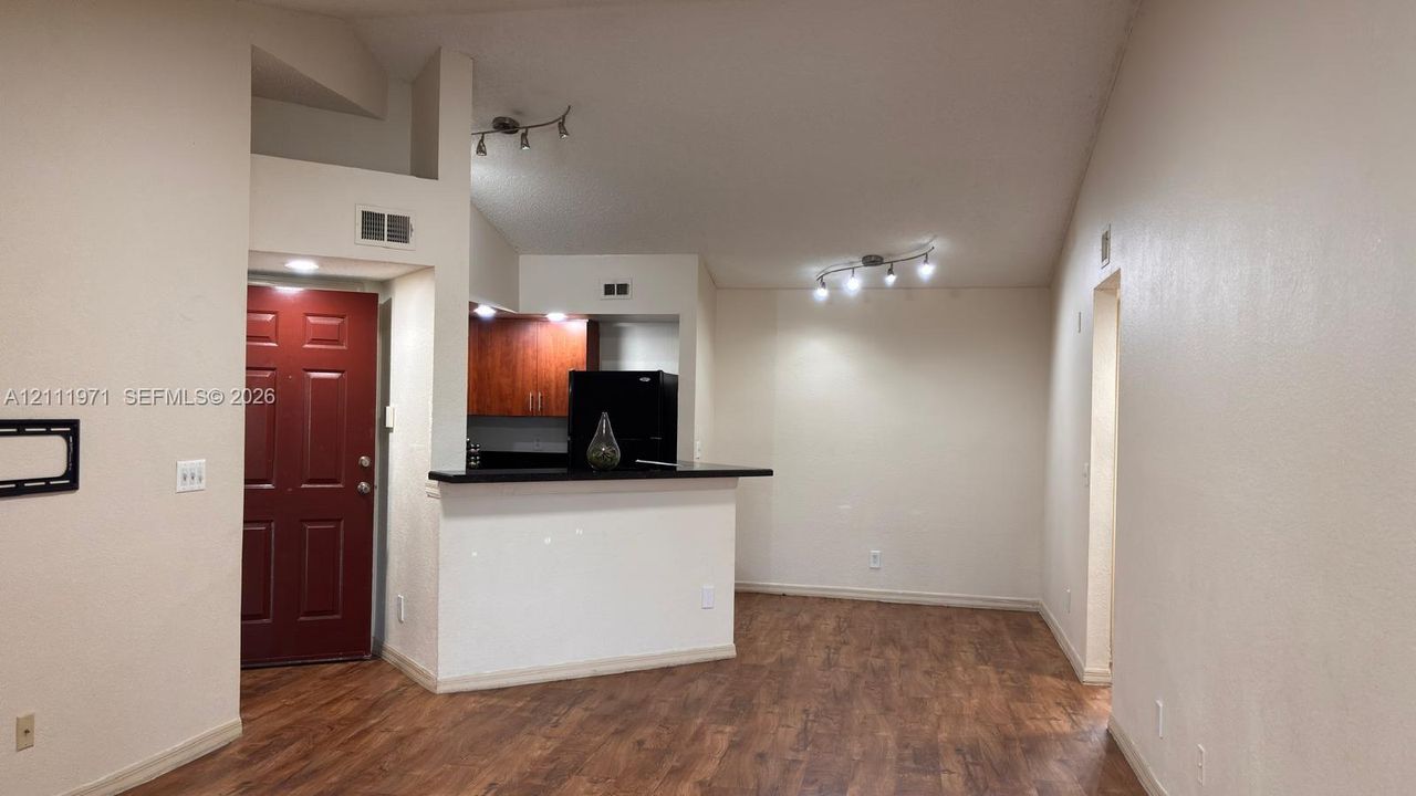 Vaulted ceilings, wood-finish flooring, breakfast bar with black countertop, and multi-directional track lighting