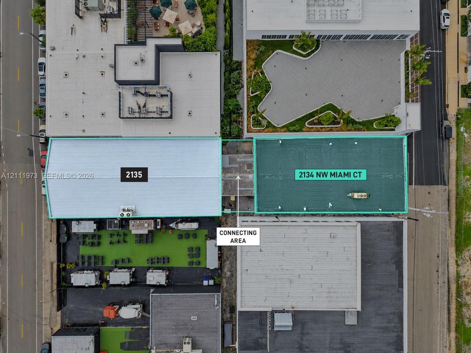 Aerial perspective of two distinct structures featuring a centralized corridor, dual-roof configurations, and surface-level hardscaping