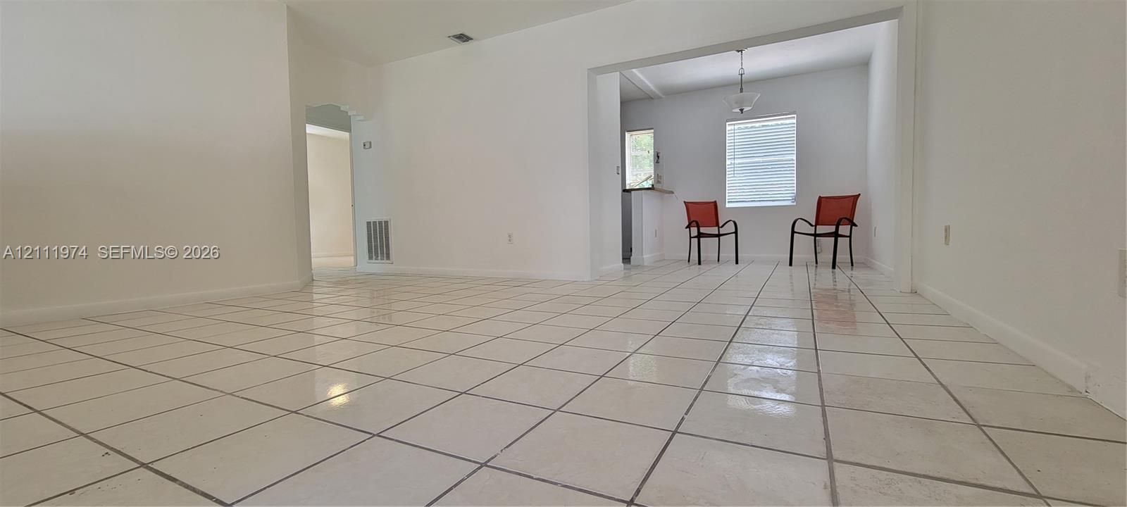 Interior space featuring white tile flooring, neutral wall paint, and an overhead pendant light fixture