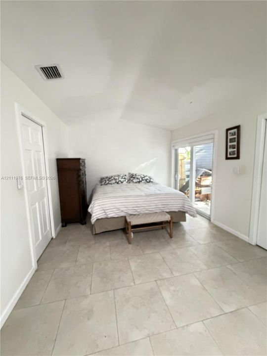Large-format neutral tile flooring and sliding glass doors with exterior access