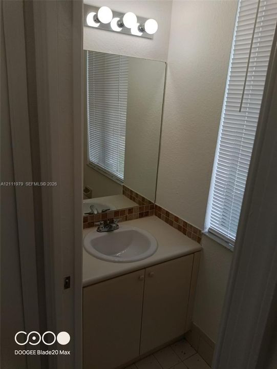 Vanity featuring a solid-surface countertop, an integrated sink basin, decorative mosaic tile backsplash, and a multi-globe light fixture