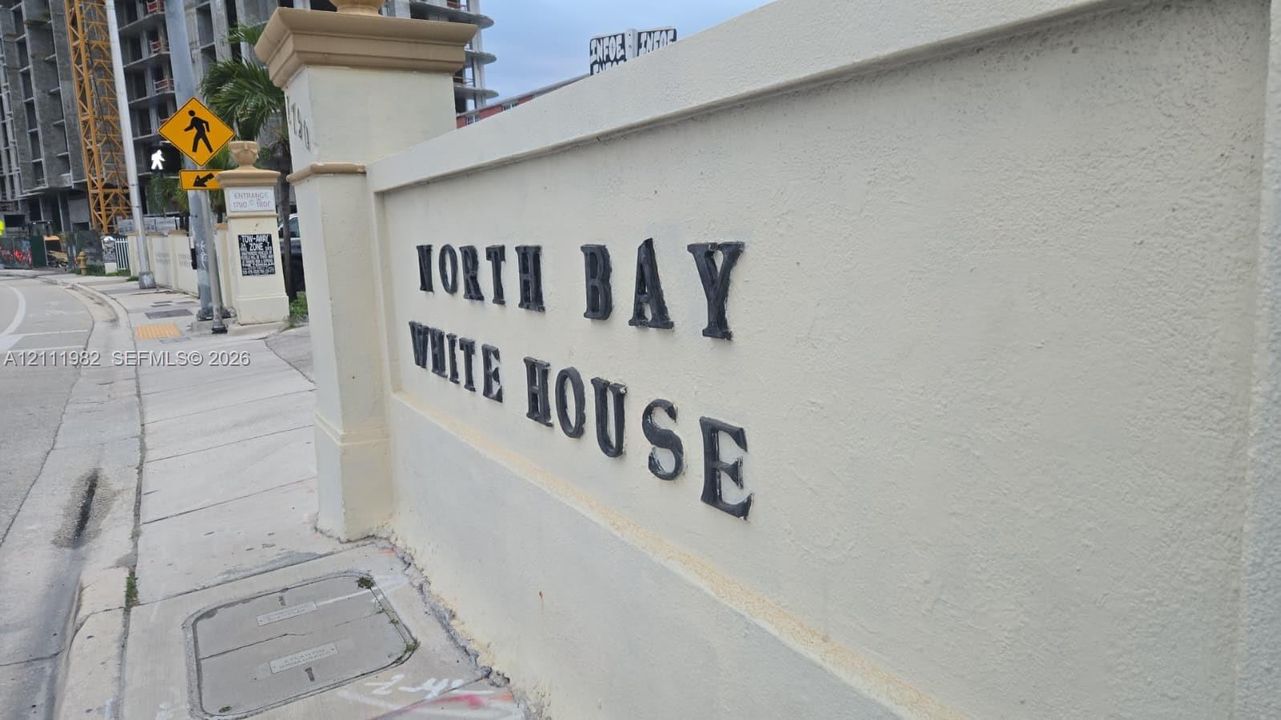 Stucco perimeter wall featuring decorative stone-capped pillars and dark dimensional lettering