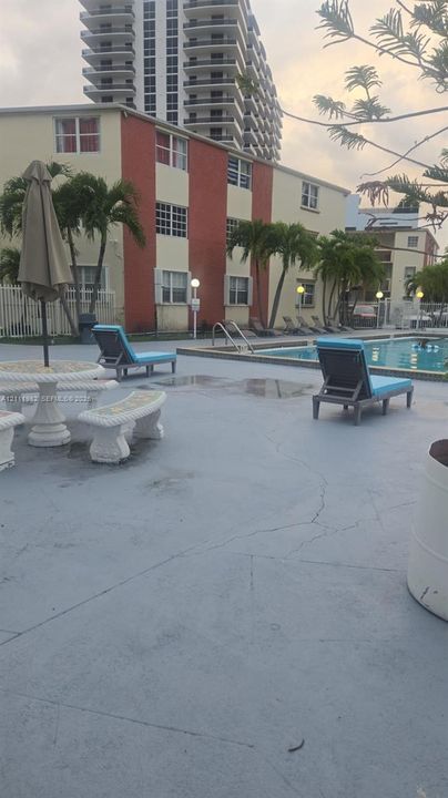 Swimming pool with concrete decking, palm trees, and multi-story building exterior
