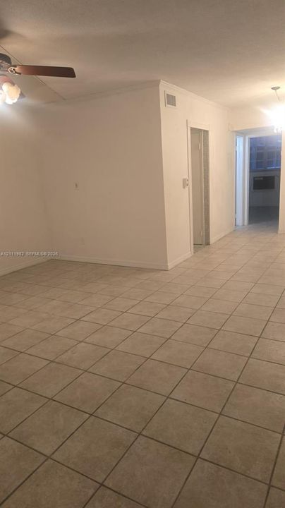 Interior space featuring neutral tile flooring, smooth wall surfaces, and a ceiling-mounted fan with integrated lighting