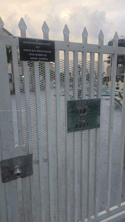 White metal gated entry with spear-top finials and integrated mesh screen