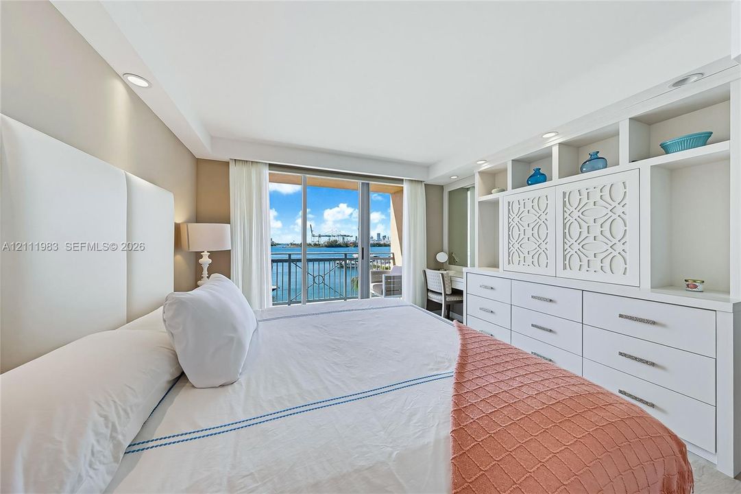 Built-in wall-to-wall cabinetry with integrated open shelving and drawers, floor-to-ceiling glass sliding doors, recessed lighting, and water scenery