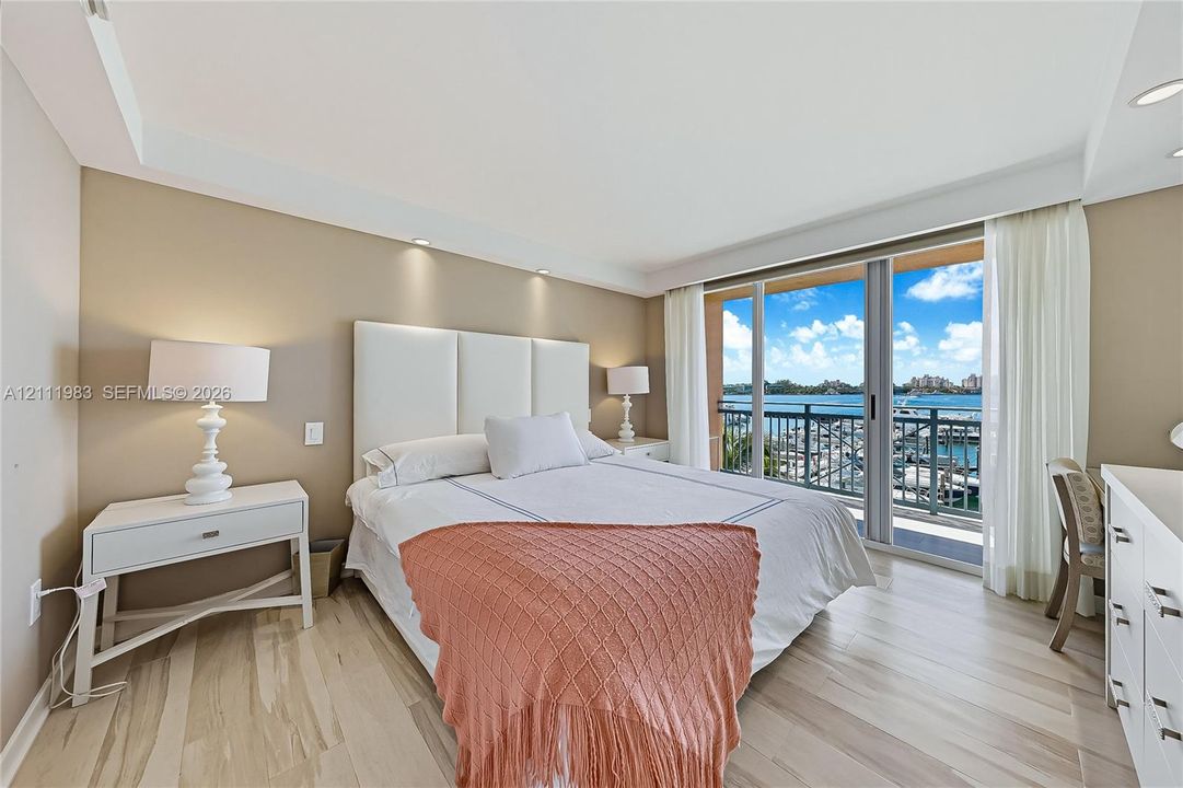 Wood-finish flooring, recessed ceiling lighting, and sliding glass doors opening to a balcony with water and marina scenery