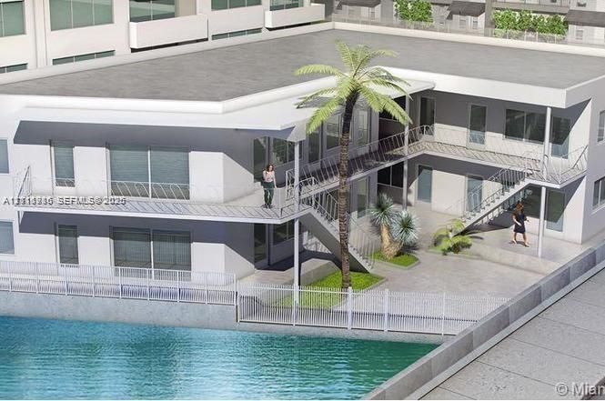 Multi-level exterior featuring white stucco siding, metal railing balconies, concrete courtyard hardscaping, and built-in metal staircases overlooking a waterfront boundary