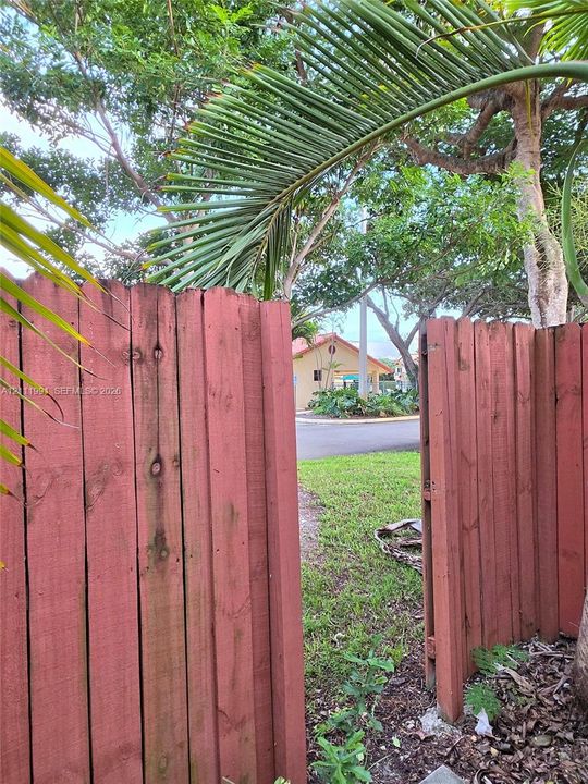 Private outdoor patio featuring concrete pavers, wood-style privacy fencing, and mature palm landscaping