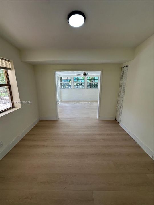 Neutral-toned interior featuring wood-finish flooring, a flush-mount overhead light fixture, bi-fold closet doors, and multi-pane windows