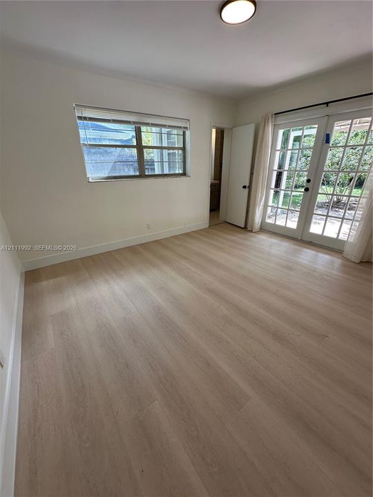 Light-filled interior featuring wood-finish flooring, white walls, and French doors