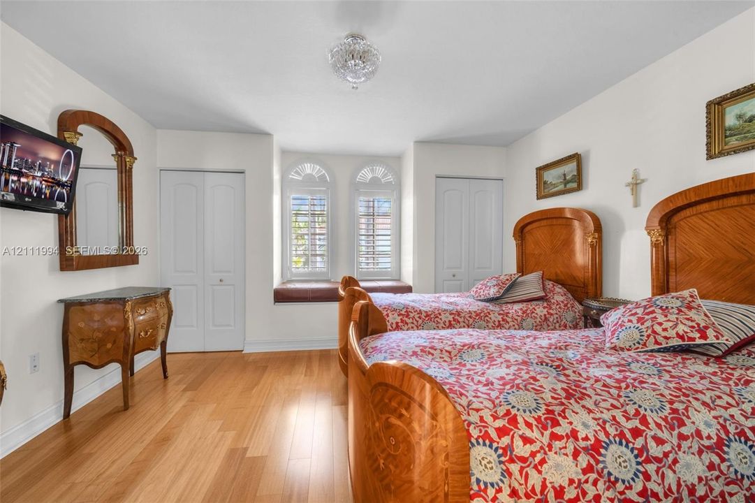 Wood-finish flooring, dual arched windows with integrated seating, and two sets of interior closet doors
