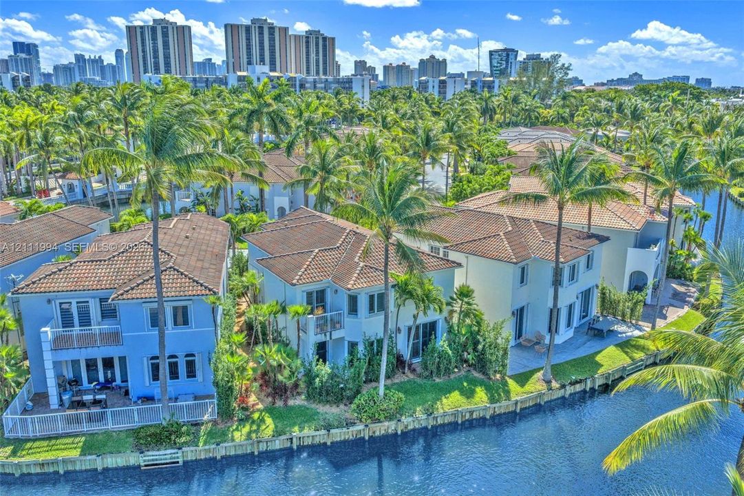 Waterfront residential property featuring multi-story homes with tile roofing, exterior balconies, private seawall bulkheads, and landscaped grounds