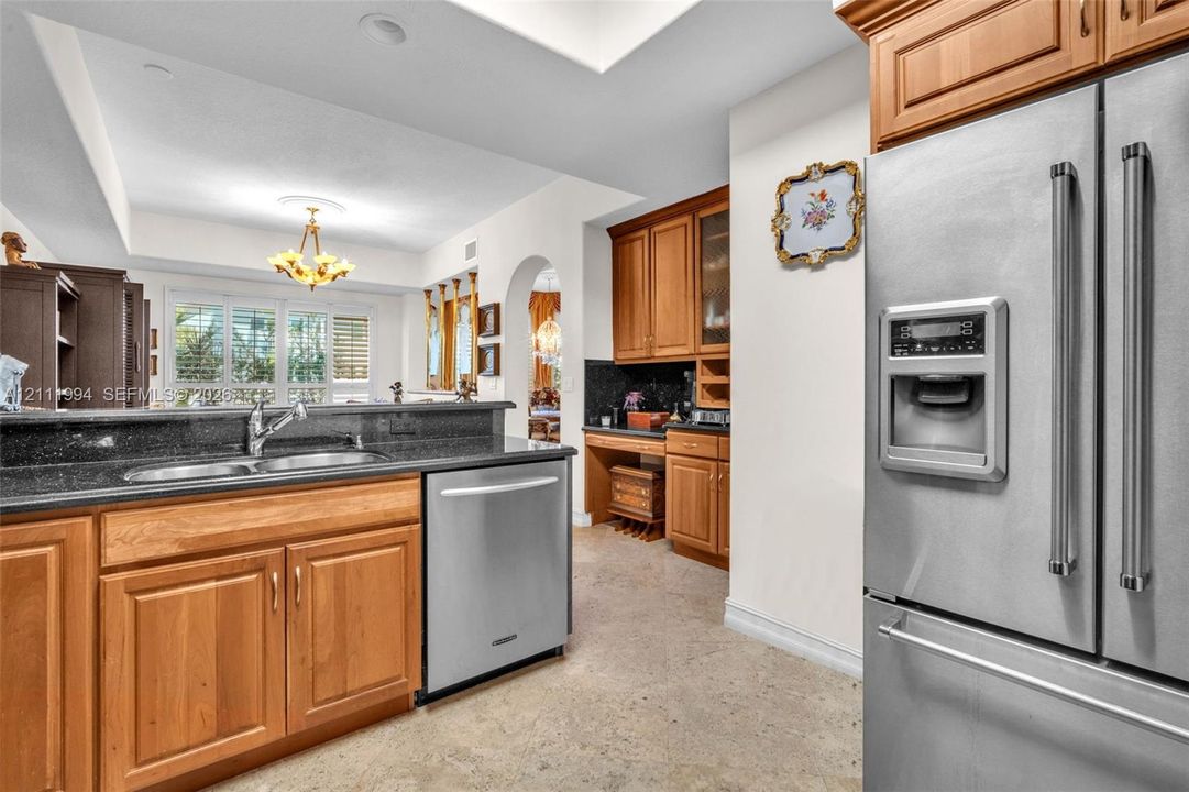 Kitchen featuring natural wood cabinetry, dark stone countertops, stainless steel appliances, a double-basin sink, and recessed lighting