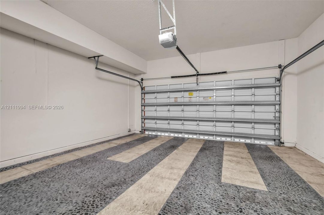 Garage featuring smooth-finish walls, a steel sectional door, and decorative aggregate concrete flooring