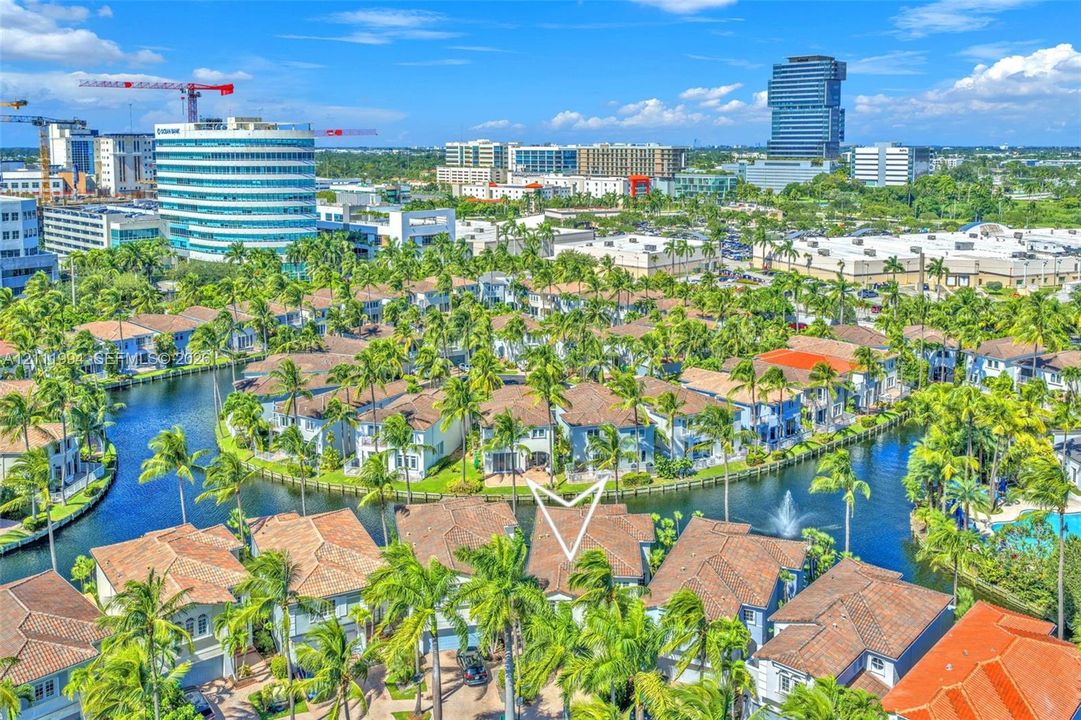 Aerial perspective of a multi-story residential structure featuring a tiled roof, positioned on a waterfront lot with canal access and surrounding tropical landscaping