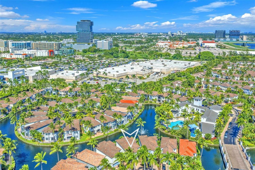 Aerial perspective of a multi-unit residential community featuring clay tile roofing, canal-front positioning, water features, and lush tropical landscaping