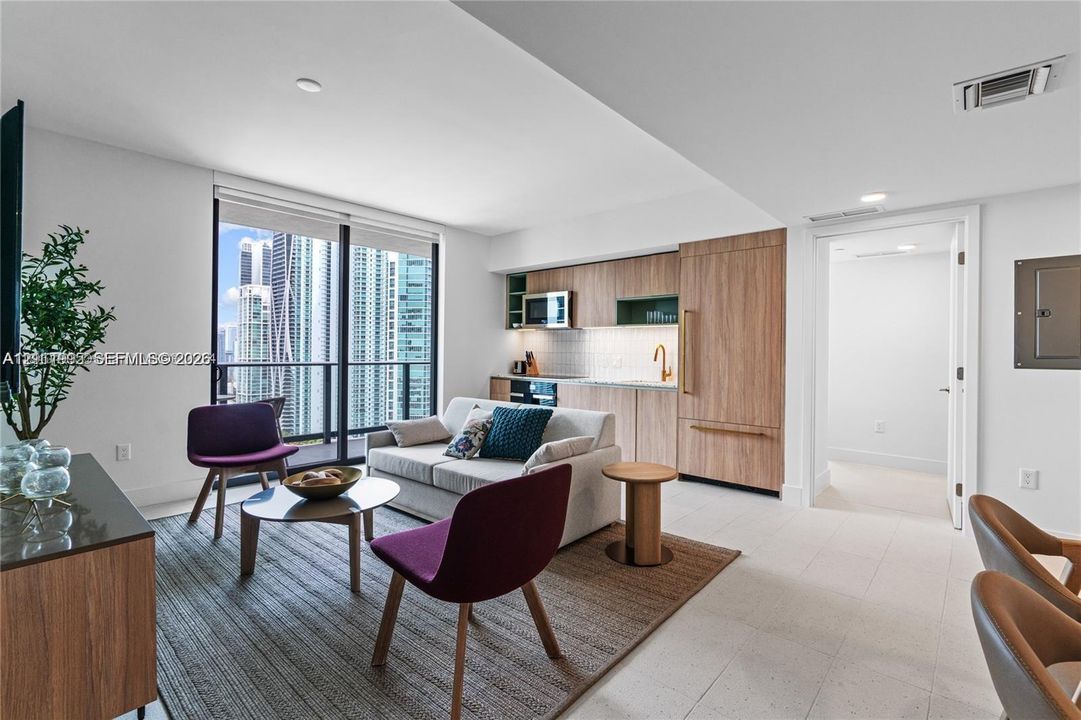 Open-concept kitchen featuring wood-finish cabinetry, integrated refrigerator, and light tile flooring, illuminated by expansive floor-to-ceiling glass paneling