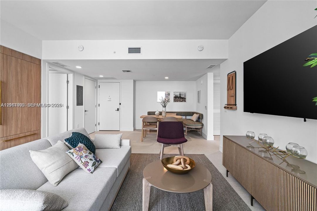 Open-concept interior featuring light neutral wall tones, wood-finish cabinetry, and recessed lighting
