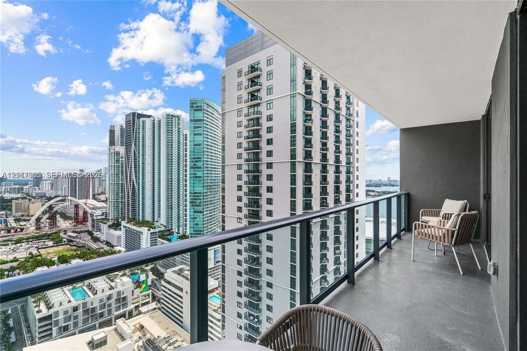 Covered balcony featuring concrete flooring and a glass-paneled railing