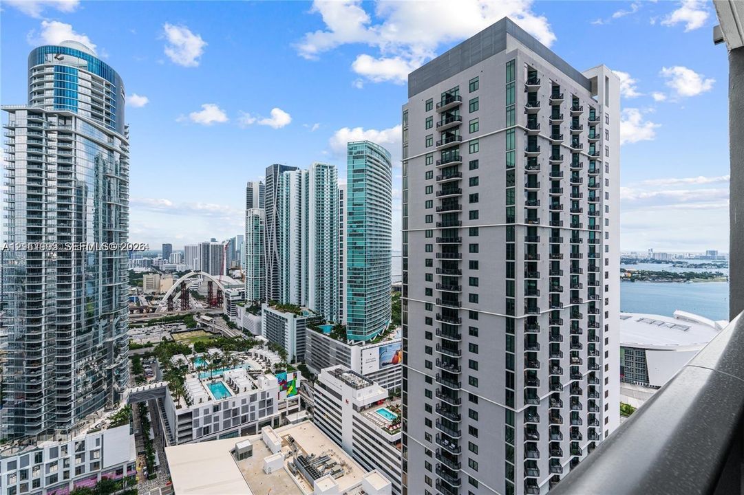 Elevated cityscape including glass-facade skyscrapers, urban infrastructure, coastal waterway, and surrounding high-density architectural developments