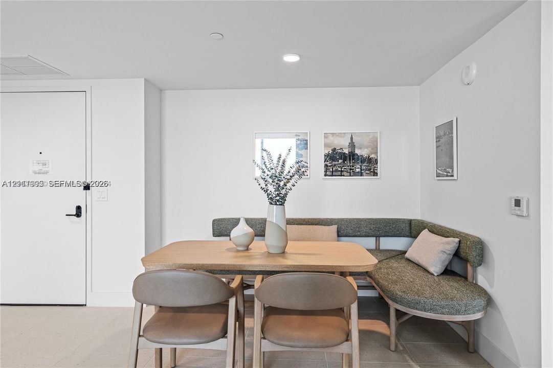 Neutral-toned tile flooring, solid-core interior door with matte black hardware, and recessed ceiling lighting