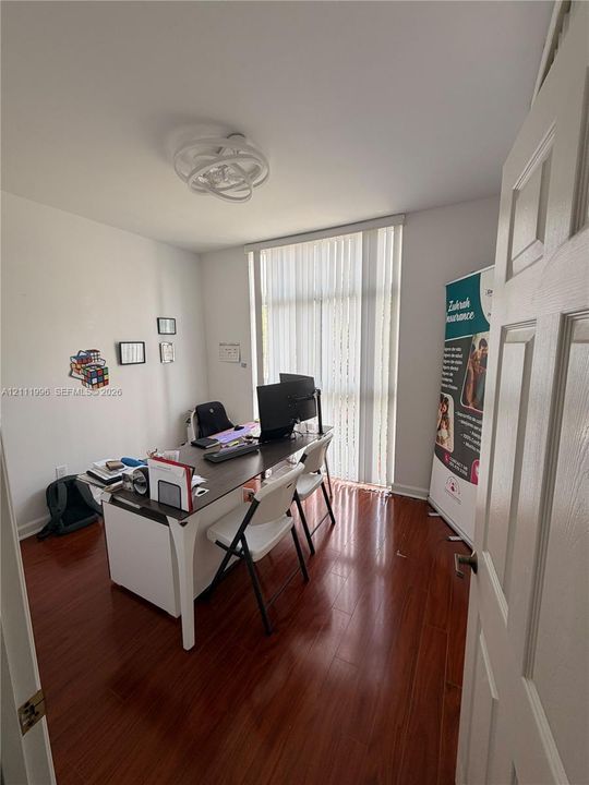 Wood-finish flooring, floor-to-ceiling window with vertical blinds, and contemporary circular ceiling fixture