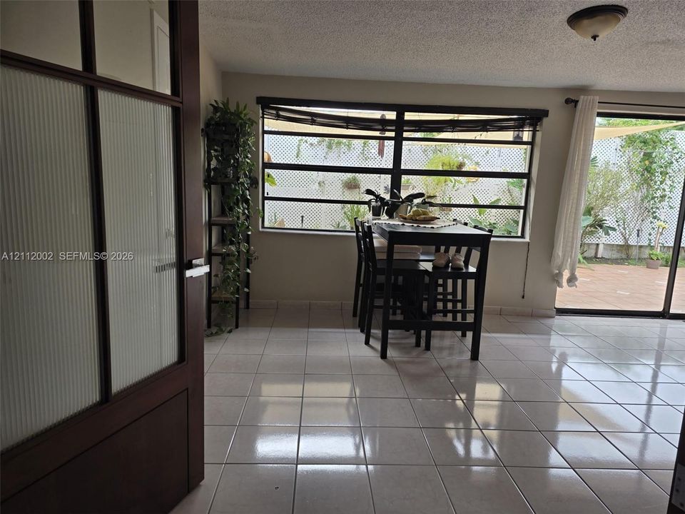 Interior space featuring large-format ceramic tile flooring, horizontal multi-pane windows, and a sliding glass door providing external access