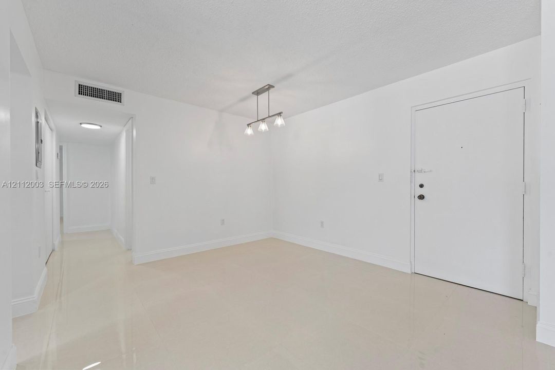 Bright interior space featuring polished tile flooring, a multi-light brushed-nickel linear pendant fixture, and a solid-core entry door