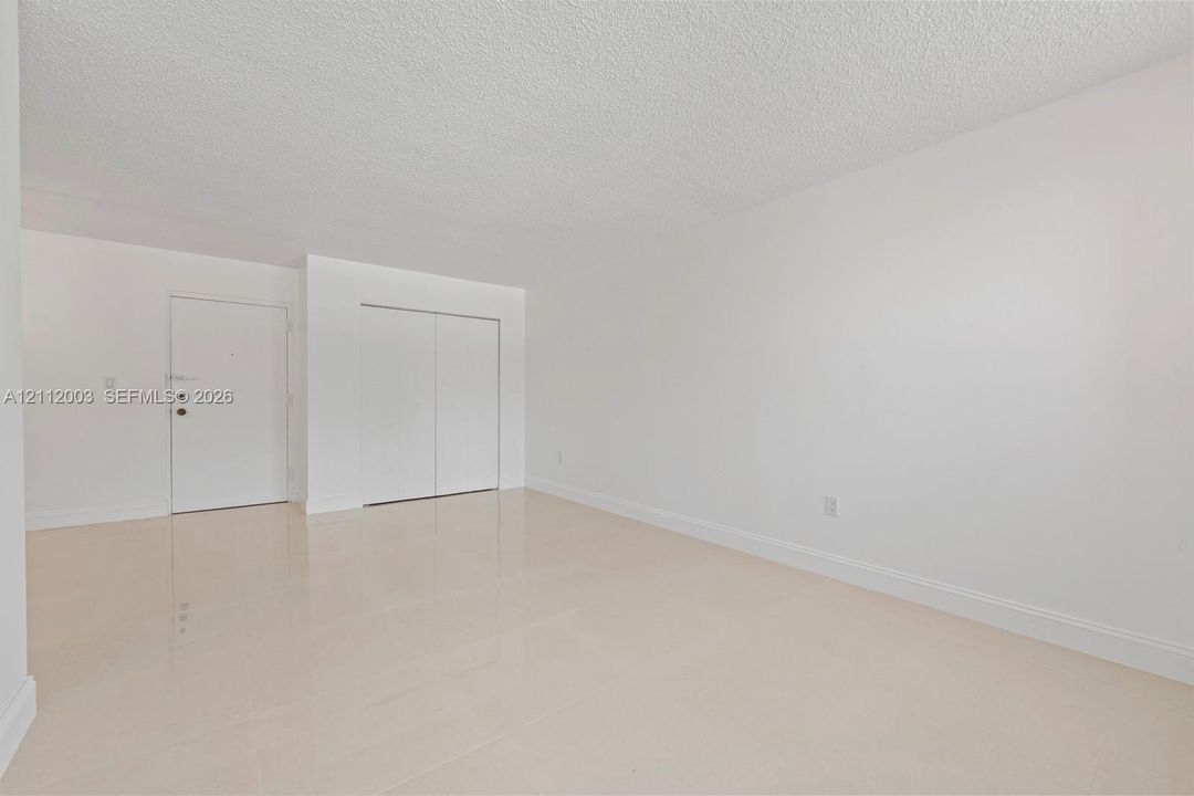 Neutral-toned interior featuring high-gloss tile flooring, textured ceiling, and a built-in closet with sliding doors
