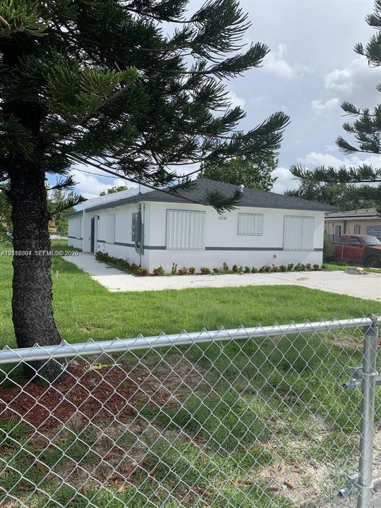 Single-story residence featuring a smooth stucco exterior, a hipped roof, metal hurricane shutters, and a concrete driveway
