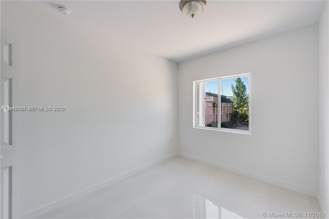 Room featuring polished tile flooring, neutral walls, a sliding glass window, and a flush-mount ceiling light fixture