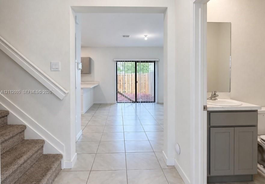 Tile flooring, gray vanity with stone countertop, neutral wall paint, and sliding glass door