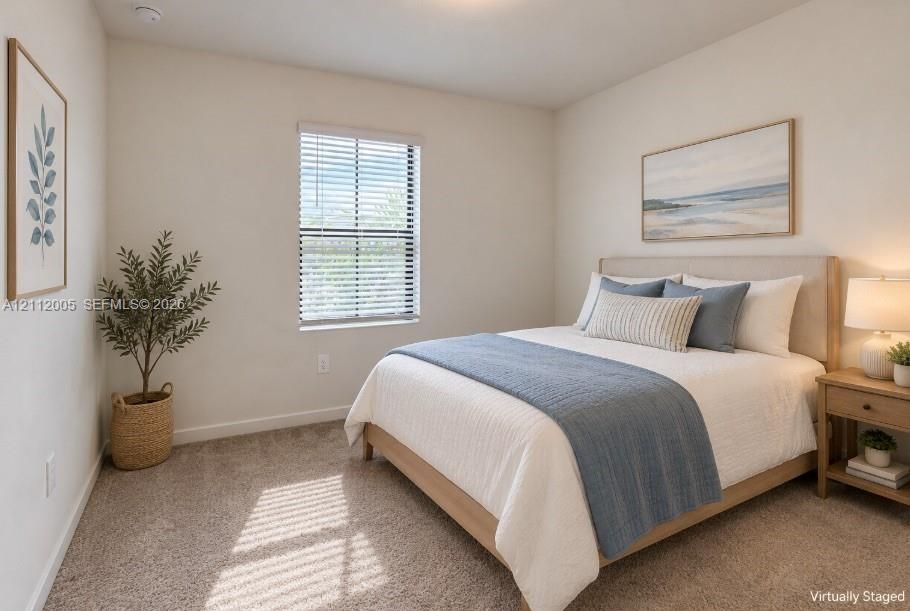 Neutral-toned interior room featuring wall-to-wall carpeting and a single-hung window with horizontal blinds