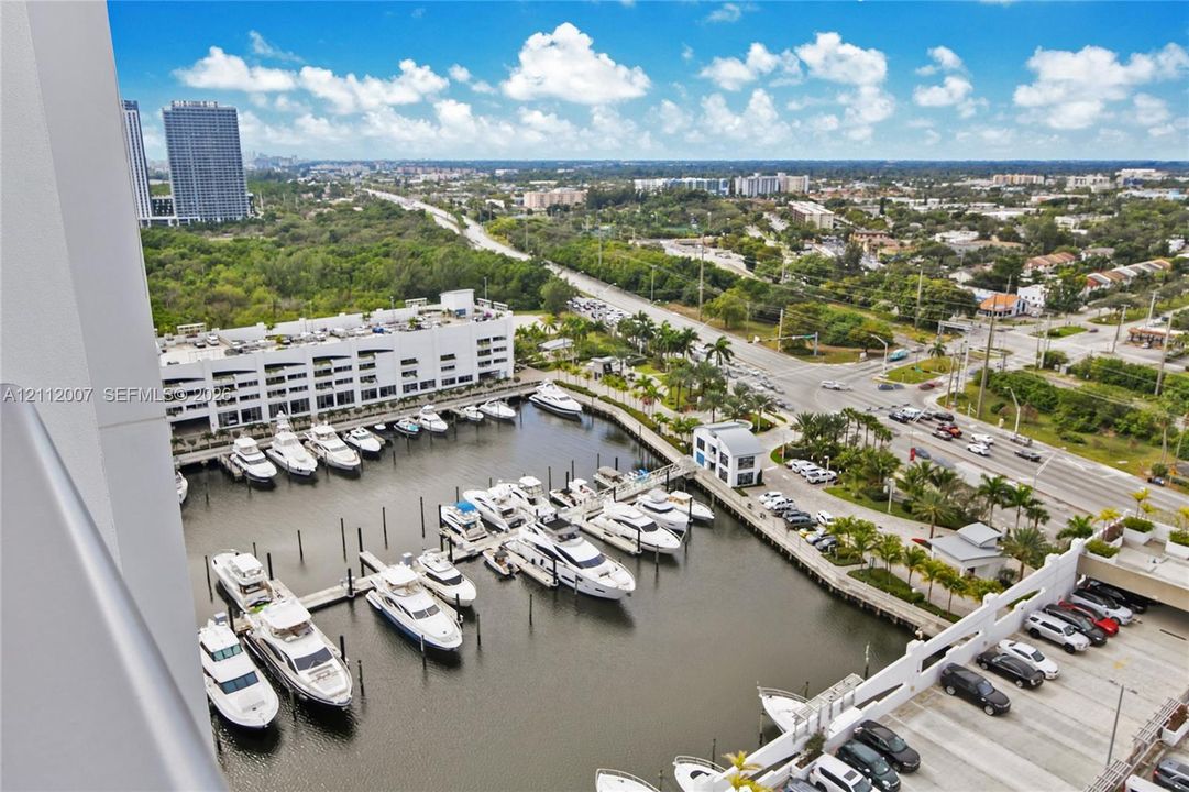 Elevated perspective featuring a private marina with multiple deep-water boat slips, concrete docking structures, and paved parking areas