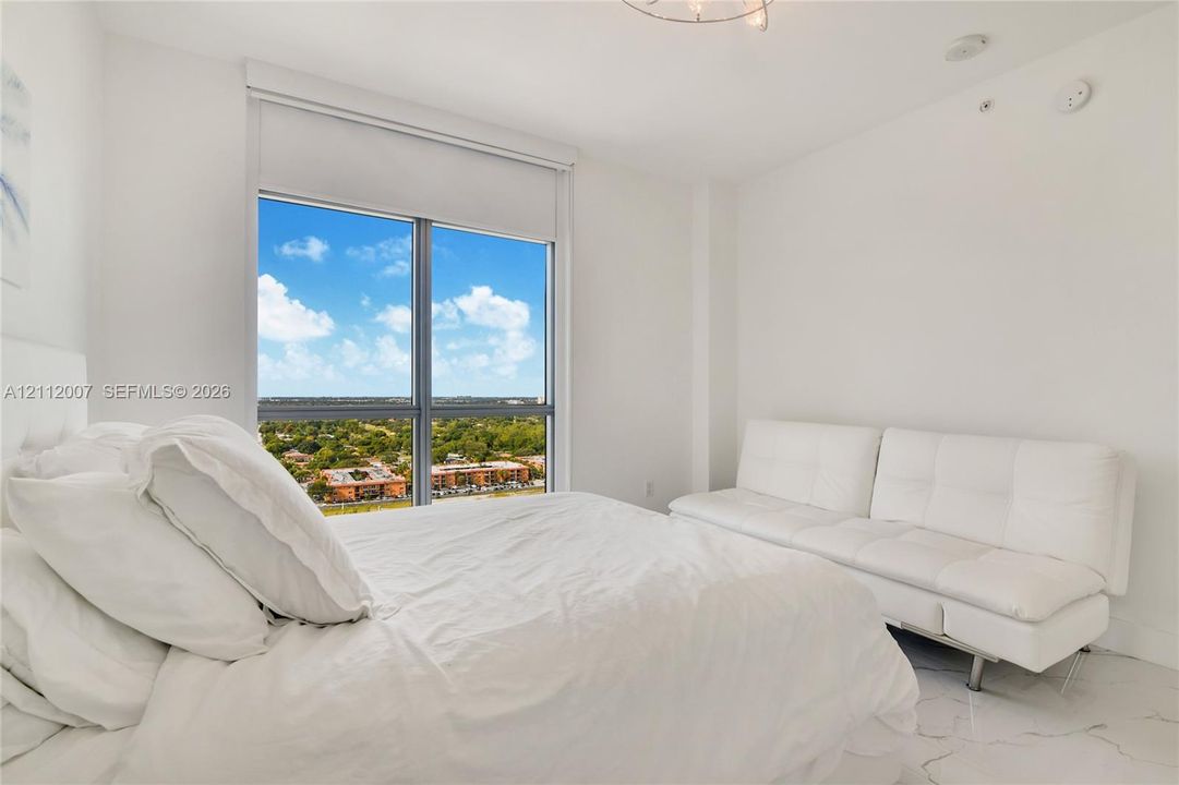 Floor-to-ceiling window featuring a roller shade and natural light, complemented by polished stone-finish flooring